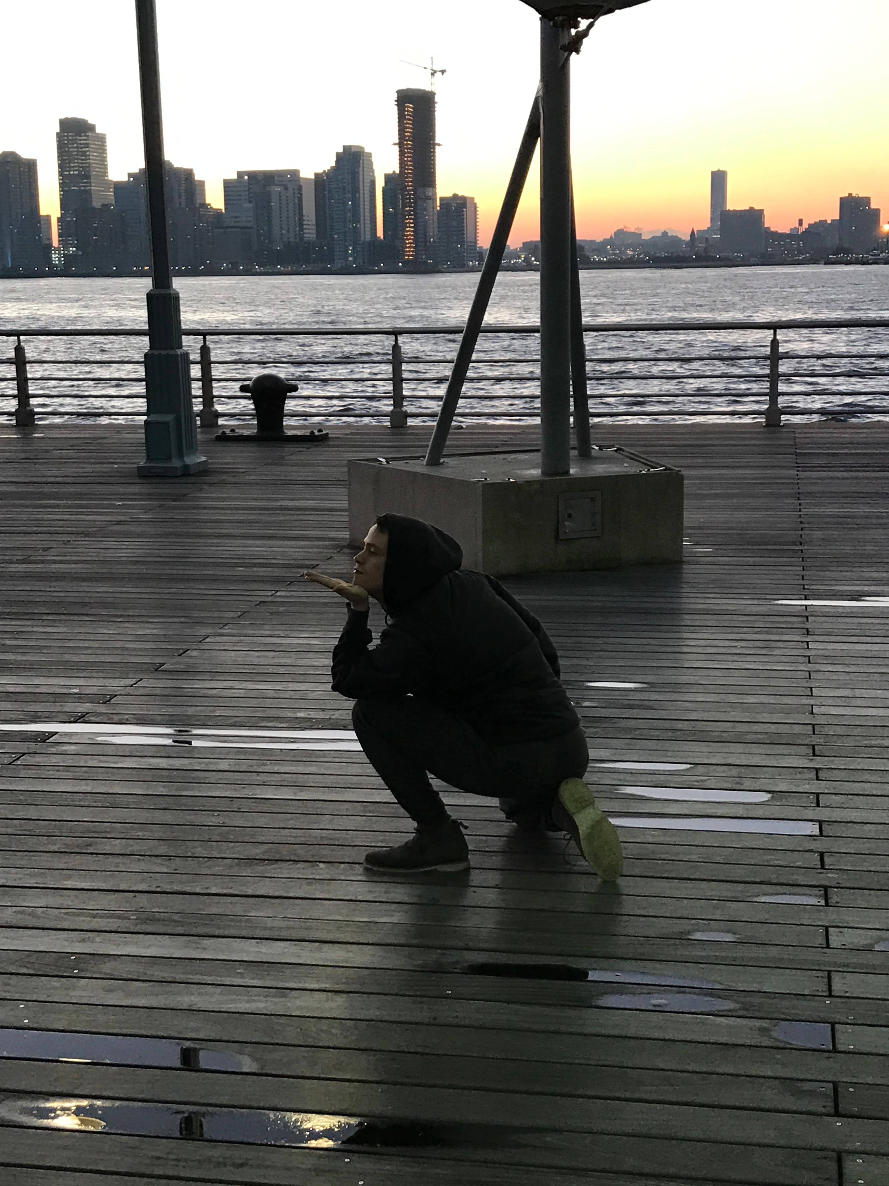 Russell dancing on a pier as another person photographs him.